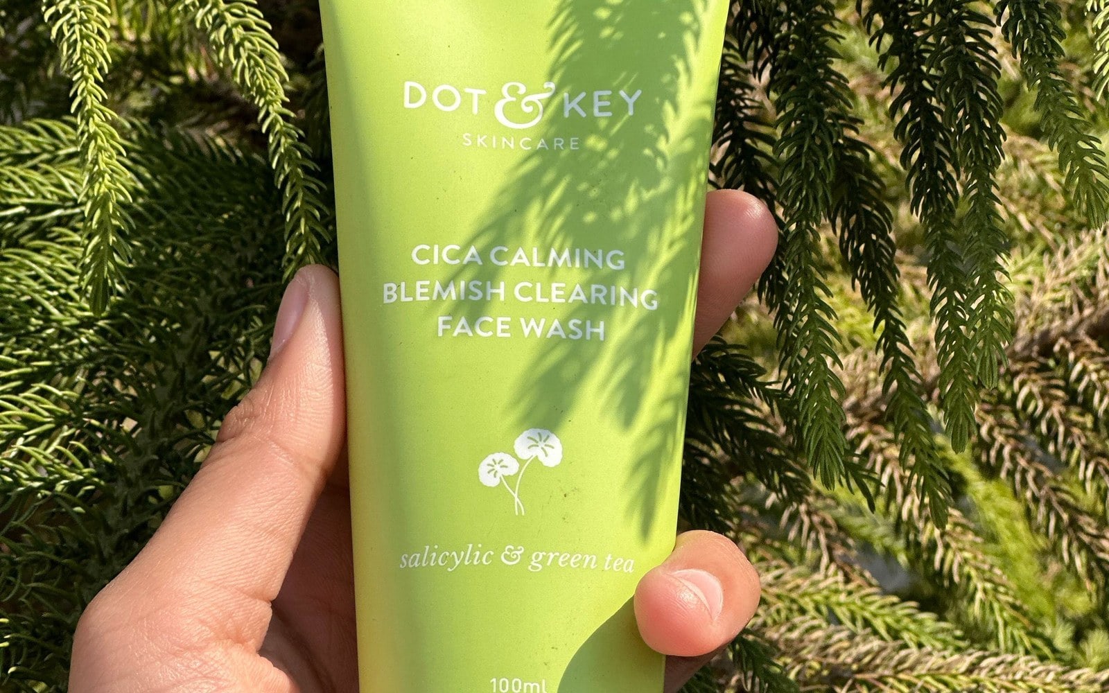 Dot & Key Cica Calming face wash held against green leaves