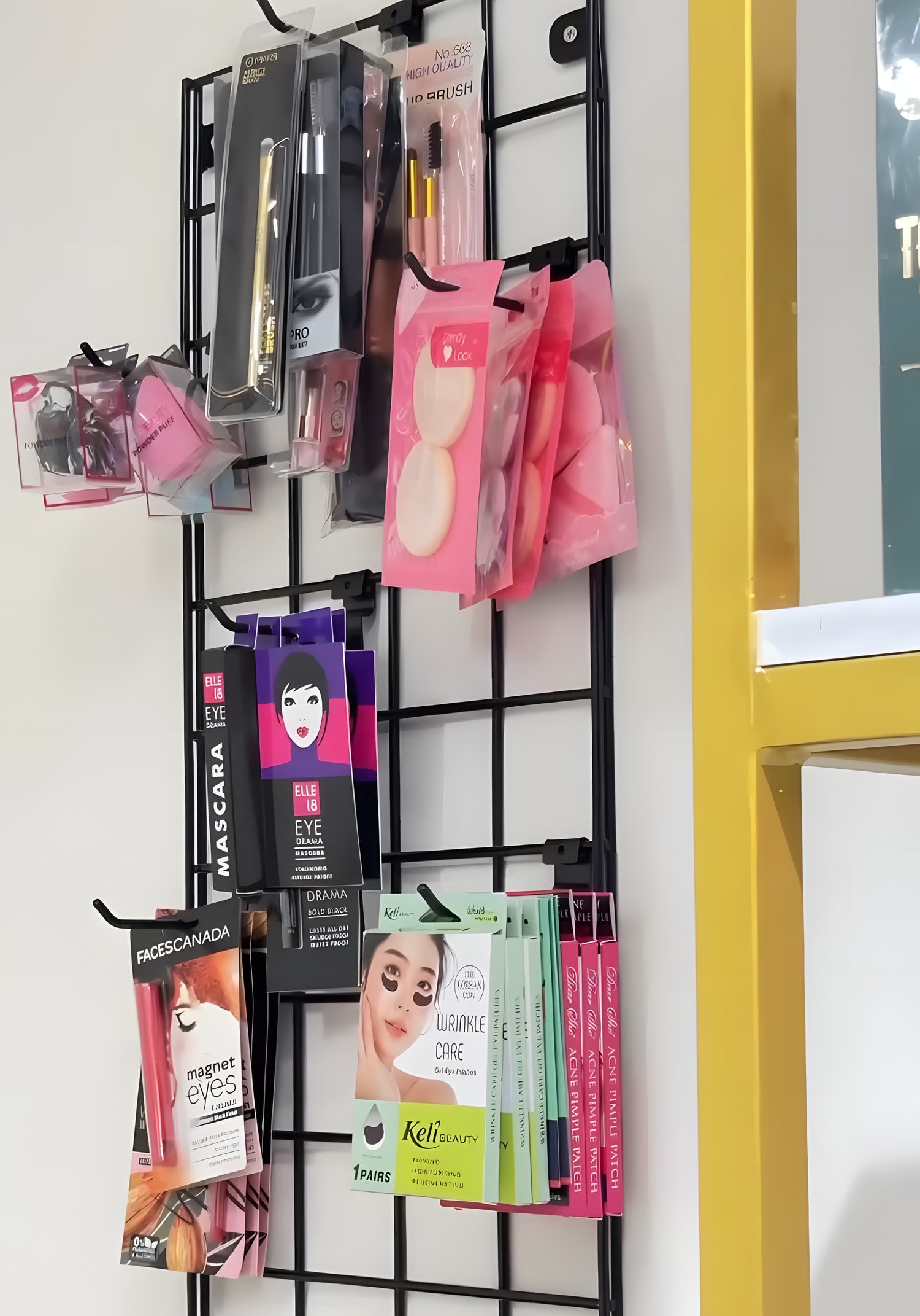 A wall grid of makeup tools, sponges and sheet masks beside the brass shelves