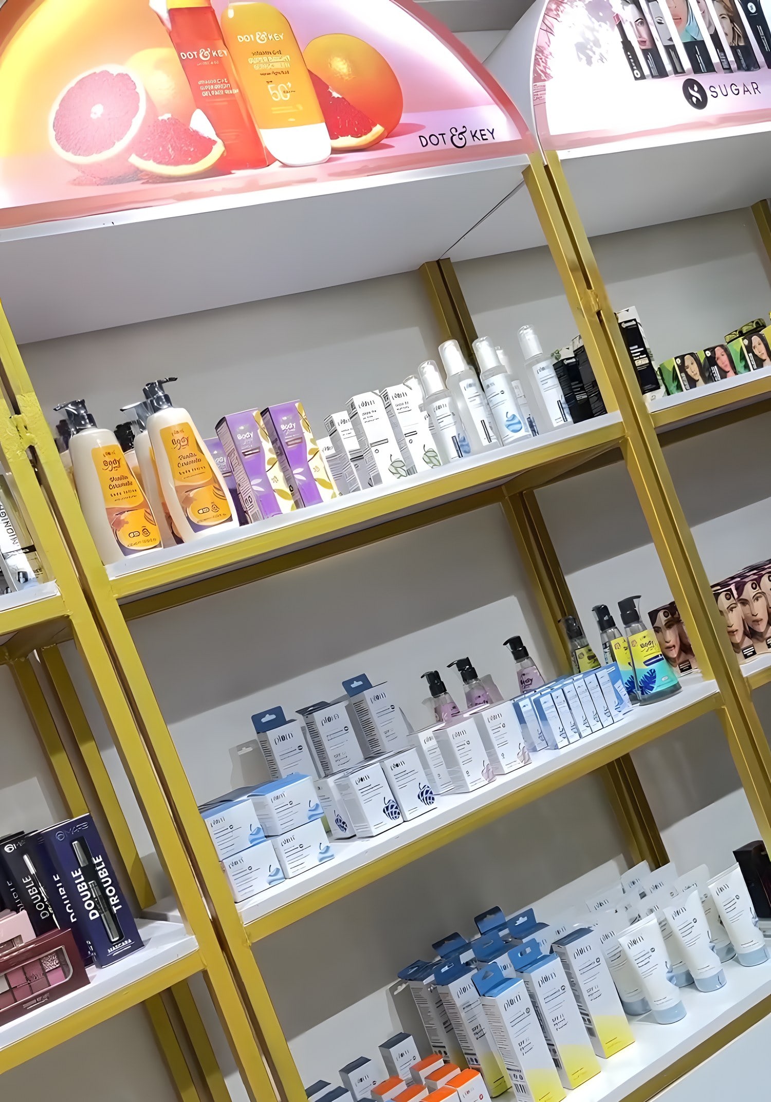 Brass-framed shelves of skincare under lit Dot & Key and SUGAR arches